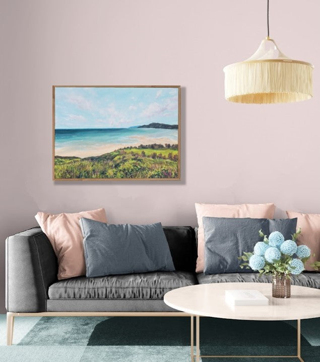 Living room with a gray sofa, coffee table, and wall art of a beach scene.