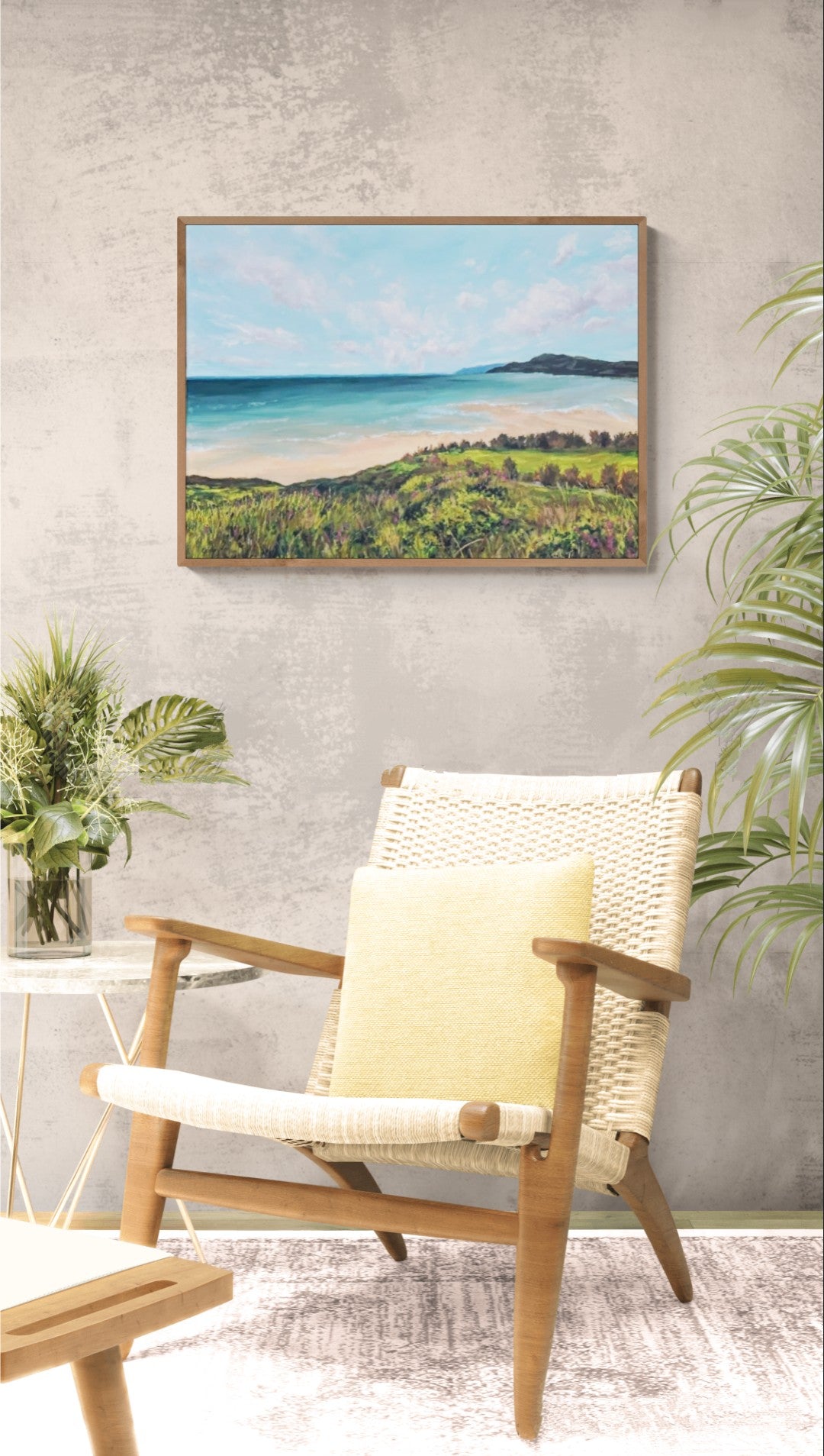 Framed original artwork for sale of a beach scene above a chair in a room with plants.