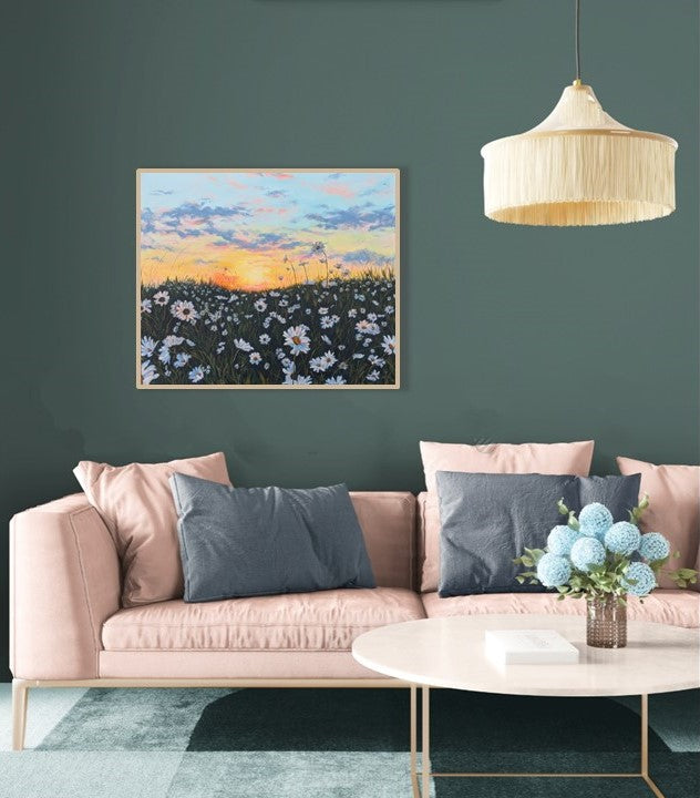 Large floral landscape painting in living room with pink sofa and green walls. Canvas art with wild daisies and sunset sky.