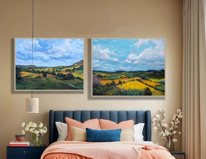 Bedroom with blue upholstered bed, orange bedding, and two countryside landscape paintings on the wall.