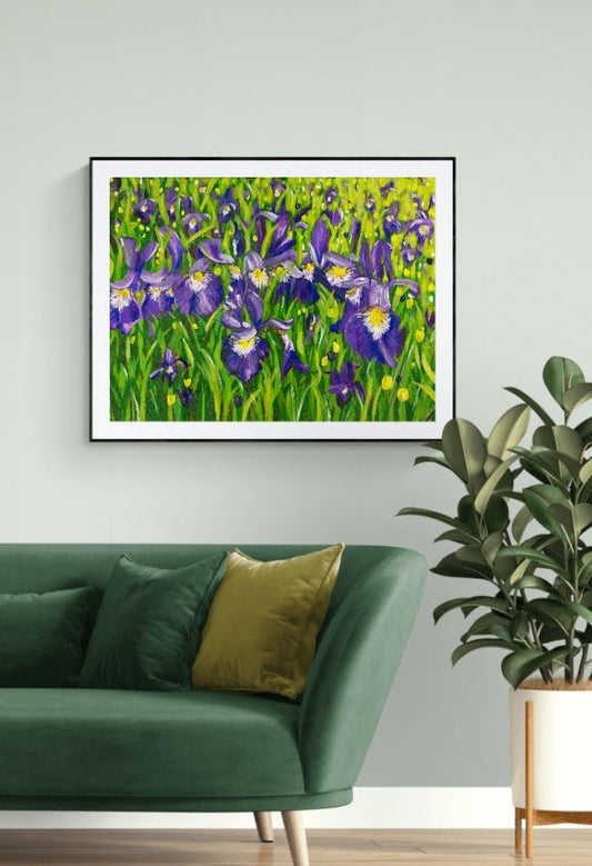 Iris landscape acrylic painting in expressive style. Bold purple, yellow, white, green with leaves and flowers. Framed in black by Judy Century Art. Shown hanging on white wall above green sofa.