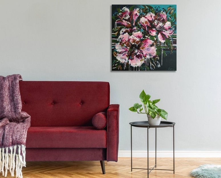 Abstract Floral Wall Art by Judy Century. Vibrant, expressive flower painting in pinks, greens and blues. Home Decor ideas - painting shown on grey wall next to red sofa and above a black coffee table with plant.