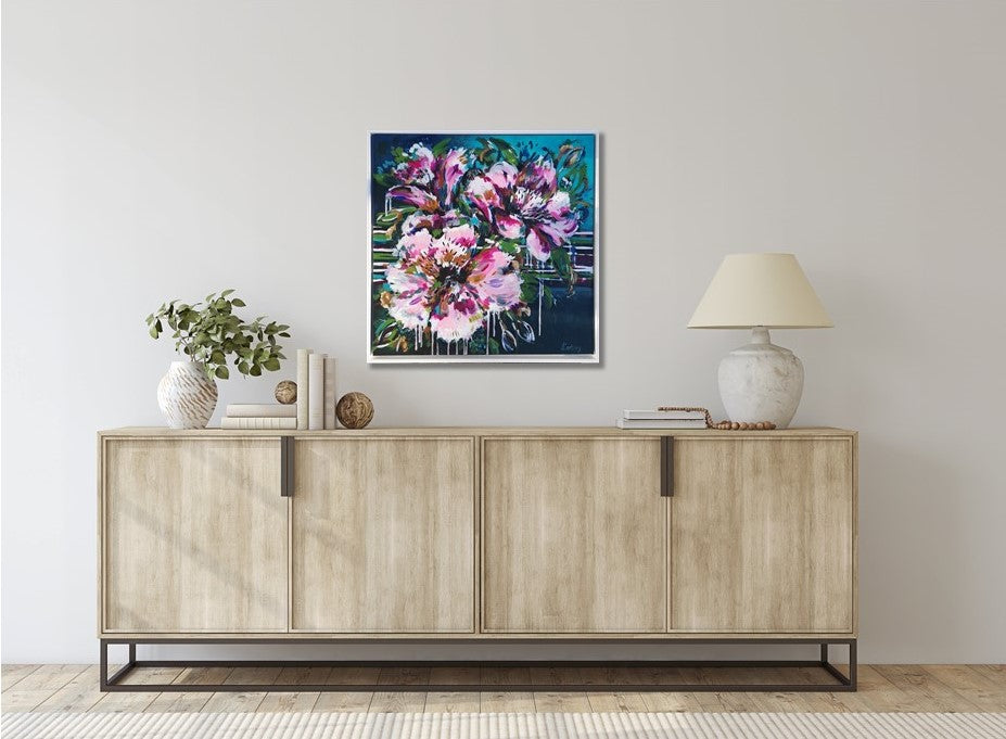 Abstract Floral Wall Art by Judy Century. Vibrant, expressive flower painting in pinks, greens and blues. Interior decor inspiration hanging on white wall above wooden sideboard.
