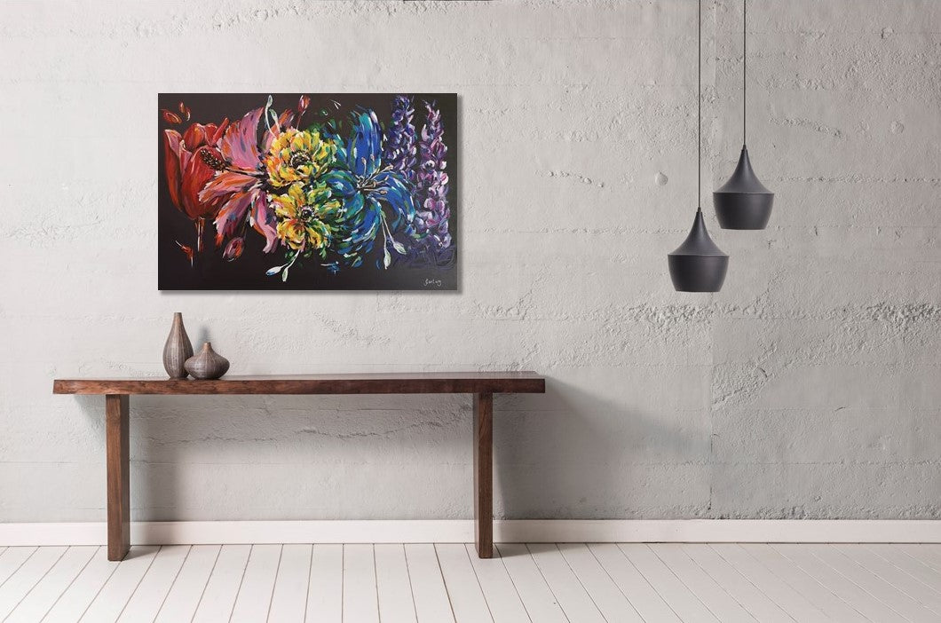 Rainbow flower painting on contrasting black background by Judy Century Art. Acrylic canvas pictured hung above minimalist dark wood side table with black pendant lights and concrete wall