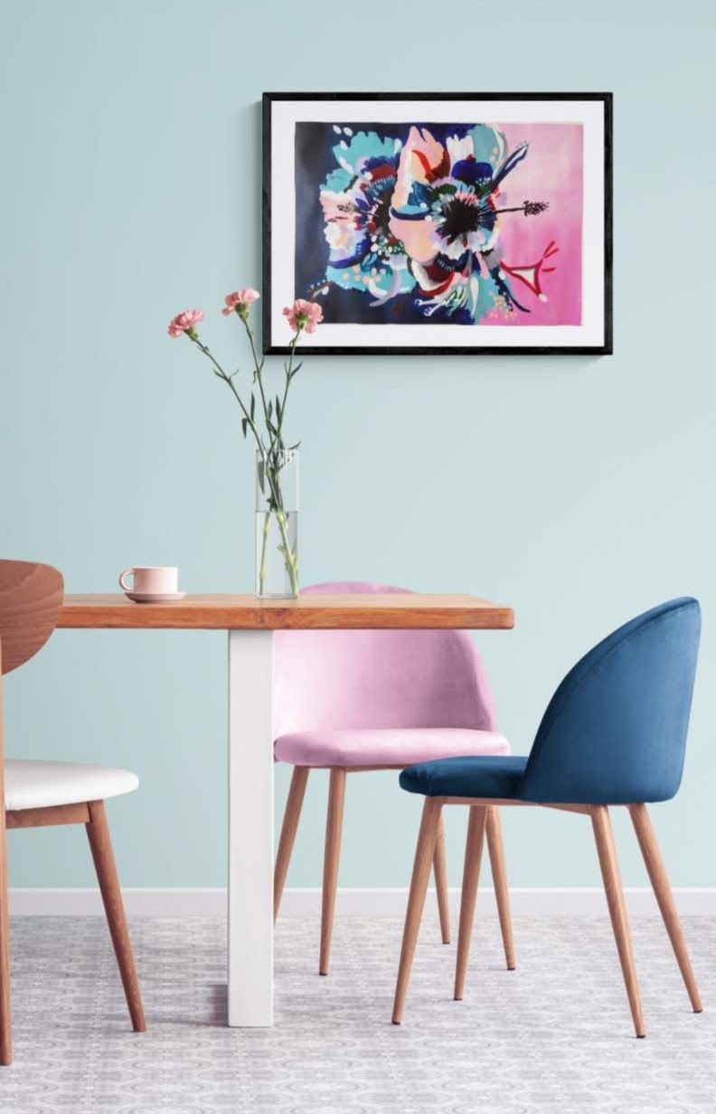 Original paper acrylic painting by Judy Century Art. Hibiscus Sorbet in black frame hanging on a navy wall above a wooden sideboard with plant in gold pot and wooden chair. Pinks, blues, teal, navy peach and white colours in elegant graphic interpretation. Shown framed in black with white mount.