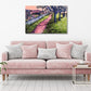 Colourful abstract landscape of an enchanting woodland scene with a shady path, trees, a river and colourful abstract bushes. Acrylic painting by Judy Century Art hanging above a pink sofa with wooden coffee table, plants and silver floor lamp