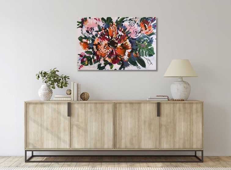 Abstract original acrylic painting by Judy Century art. 'Tropical Garden' features cheese plants, bright orange, magenta and gold flowers and floral inspired shapes. Hanging above a pale wooden sideboard with white lamp and plant