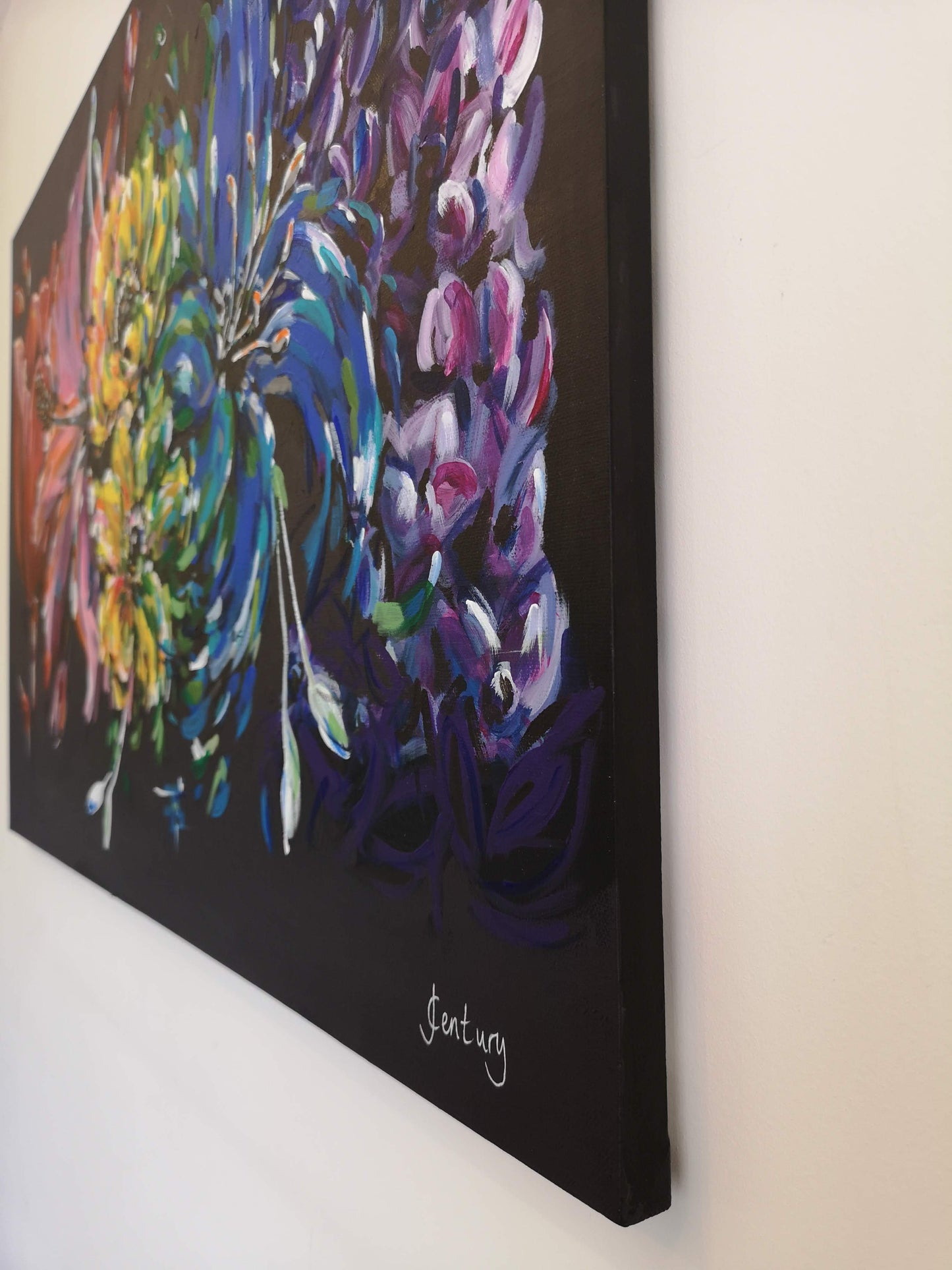 Side view of Carnival rainbow painting by Judy Century Art showing black paint wrapped around the edges for smart finish and signature in white at the bottom right corner