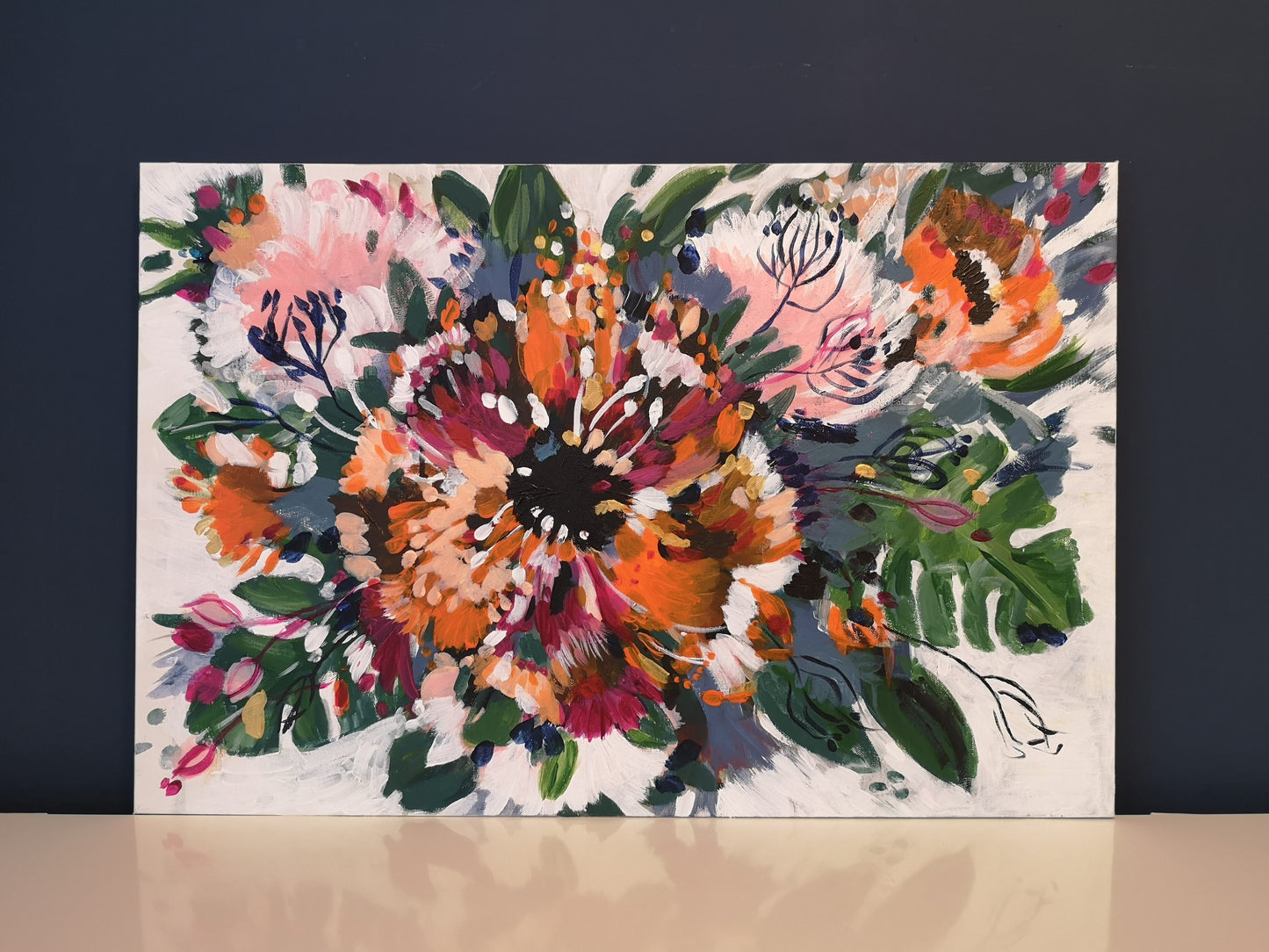 Abstract floral 'Tropical Garden' painting by Judy Century propped up against a navy wall