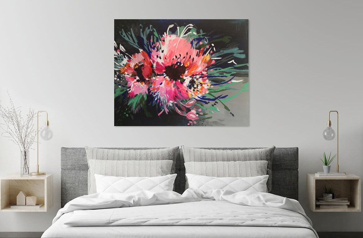 Abstract Flower Painting featuring two large bold pink blooms bursting on the page, with contrasting lines of blue, green and white extending out to add movement. Vibrant, bold and colourful original painting by Judy Century. Canvas art hanging above white bed with grey headboard. Interior decor.