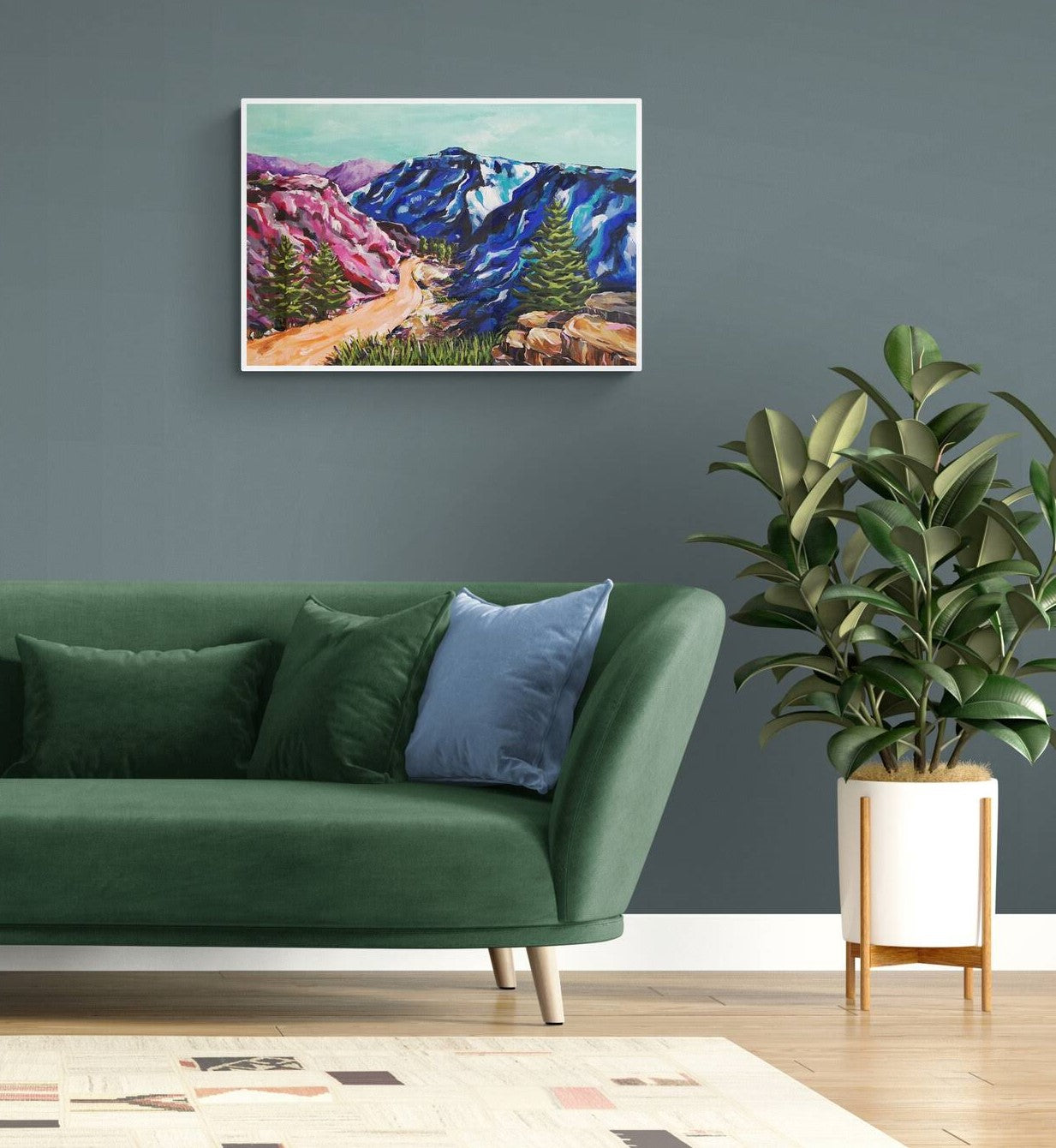 Vibrant, colourful Abstract Landscape painting by Judy Century. Mountain adventure acrylic canvas wall art hanging on blue grey wall in room with green sofa and large plant