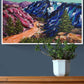 Home Decor styling of Vibrant, colourful Abstract Landscape painting by Judy Century. Mountain adventure acrylic canvas wall art hanging on navy wall above wooden chest of drawers.