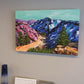 In situ picture of Vibrant, colourful Abstract Landscape painting by Judy Century. Mountain adventure acrylic canvas wall art on grey wall above fireplace.