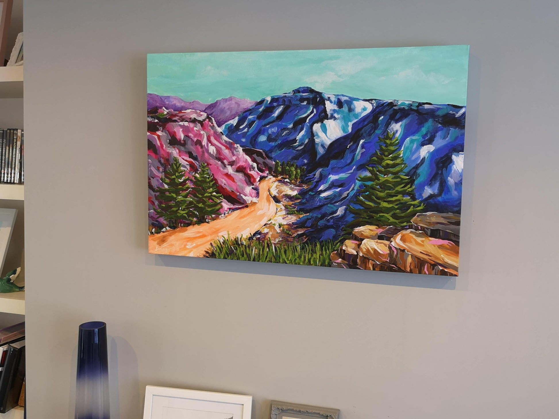 In situ picture of Vibrant, colourful Abstract Landscape painting by Judy Century. Mountain adventure acrylic canvas wall art on grey wall above fireplace.