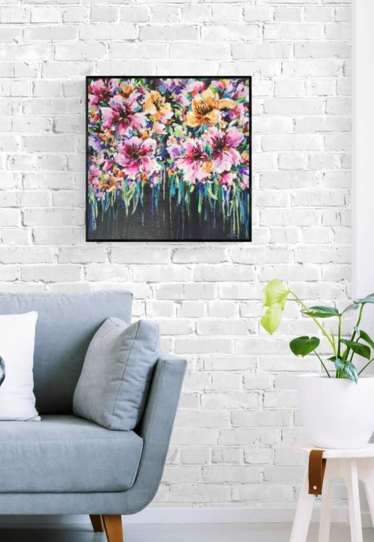 Colourful Floral Canvas painting of abstract flower bouquet by Judy Century. Shown framed in black above grey couch with white cushion against a white brick wall.