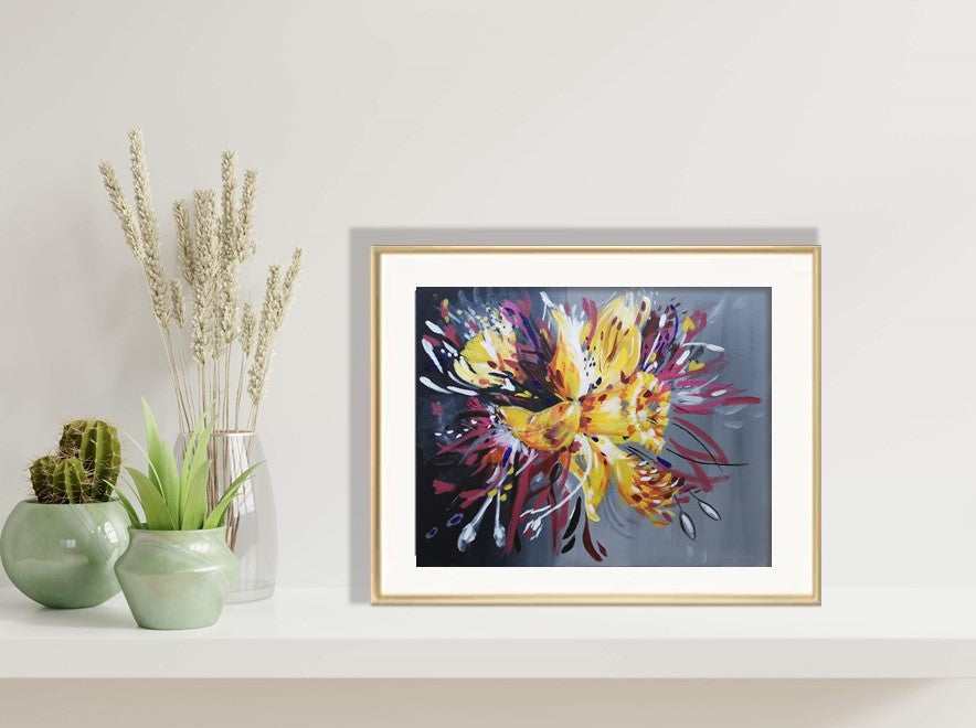 Daffodil Surprise Original painting reproduced as a fine art print framed in gold, sitting on wall shelf beside plants
