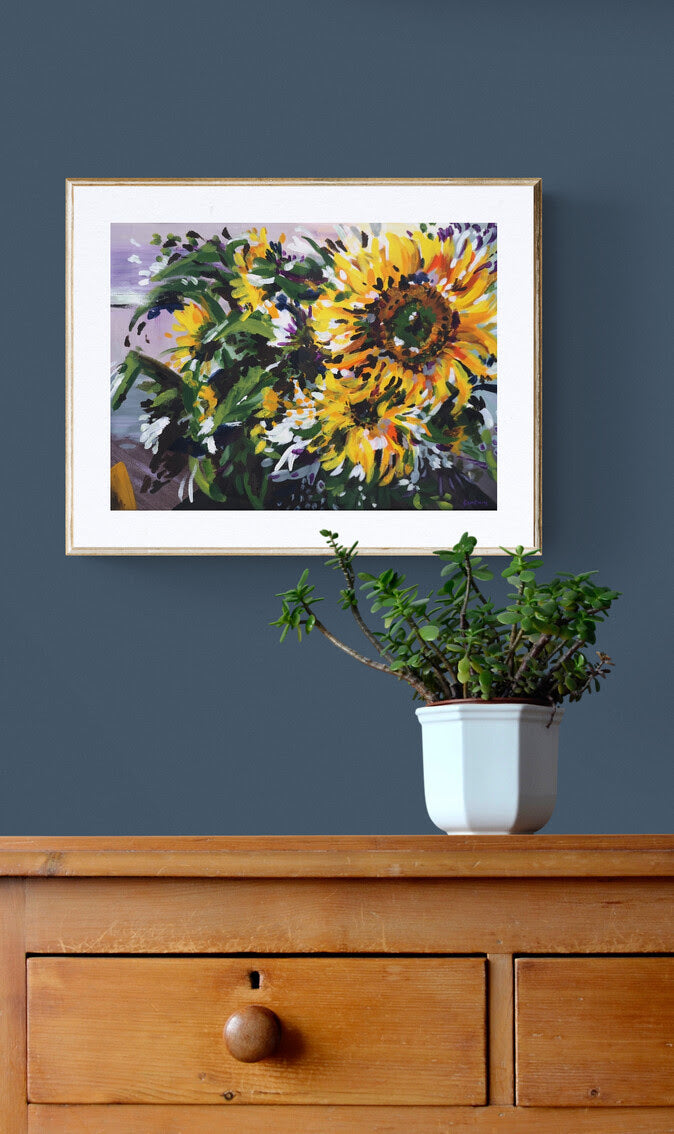 Expressive Sunflower acrylic painting on paper by Judy Century. Yellow, Green and purple wall art. shown on a navy wall above wooden sideboard.