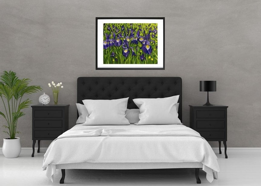 Iris landscape acrylic painting in expressive style. Hanging on a white wood wall over a black bed with white sheets and grey walls. Bold purple, yellow, white, green with leaves and flowers. Framed in black by Judy Century Art.