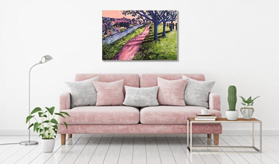 Colourful abstract landscape of an enchanting woodland scene with a shady path, trees, a river and colourful abstract bushes. Acrylic painting by Judy Century Art hanging above a pink sofa with wooden coffee table, plants and silver floor lamp