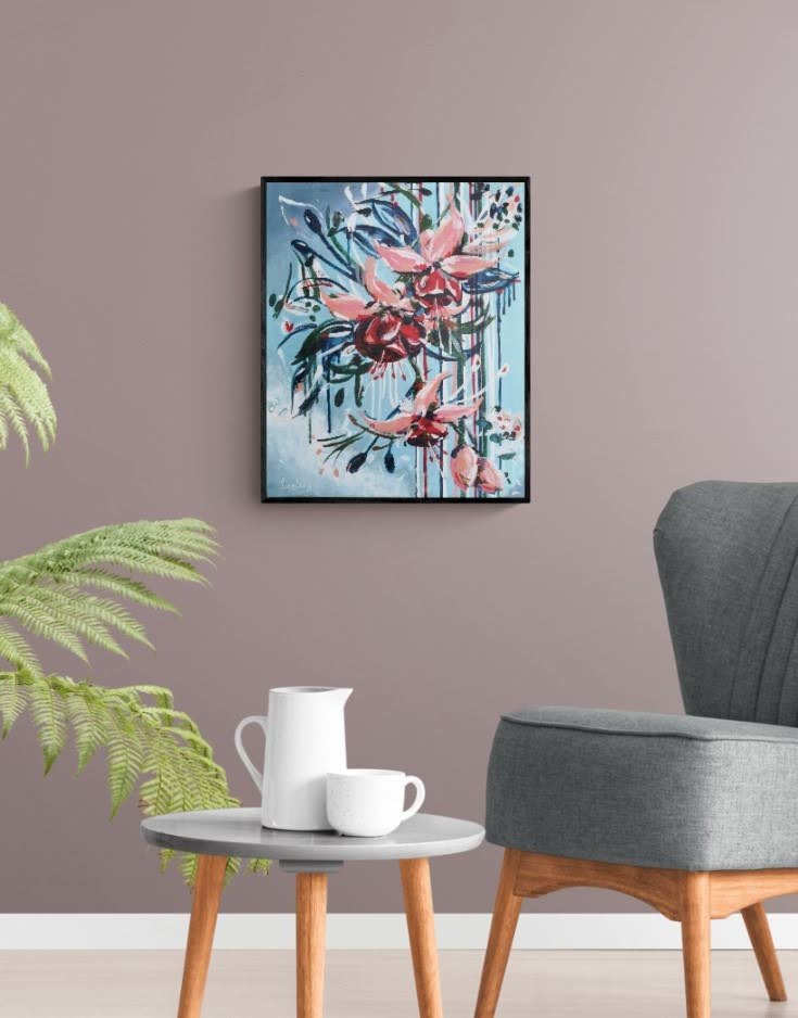 Abstract contemporary floral wall art canvas by Judy Century Art. Falling Fuscia flowers in pink and peach against a light blue background. shown in a sitting room setting with grey chair and side table