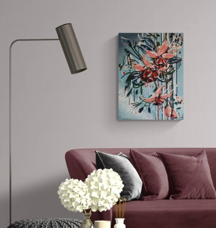 Abstract contemporary floral wall art canvas by Judy Century Art. Falling Fuscia flowers in pink and peach against a light blue background shown hanging on pale grey wall above burgundy couch