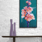 Contemporary floral painting in orange and deep green by Judy Century Art. Hanging on white brick wall above wooden console table.