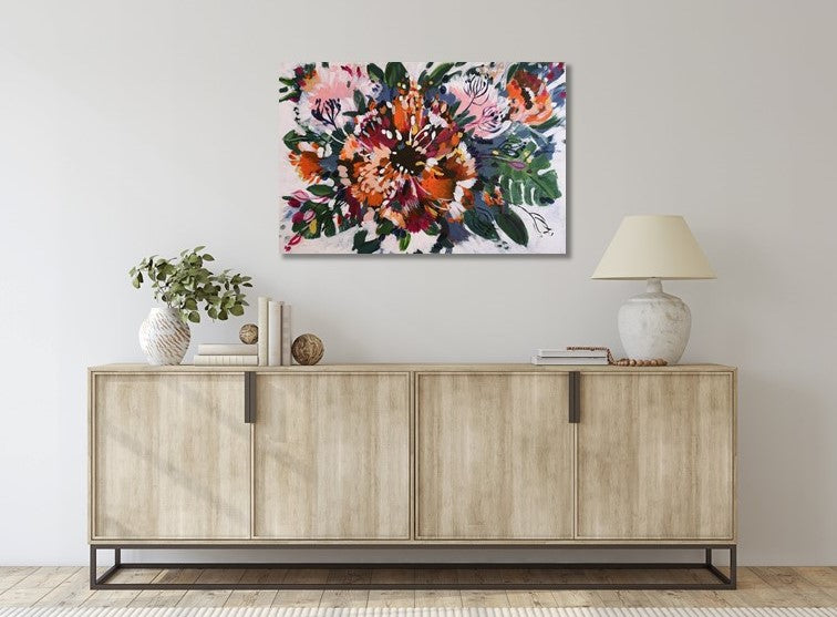 Abstract original acrylic painting by Judy Century art. 'Tropical Garden' features cheese plants, bright orange, magenta and gold flowers and floral inspired shapes. Hanging above a pale wooden sideboard with white lamp and plant