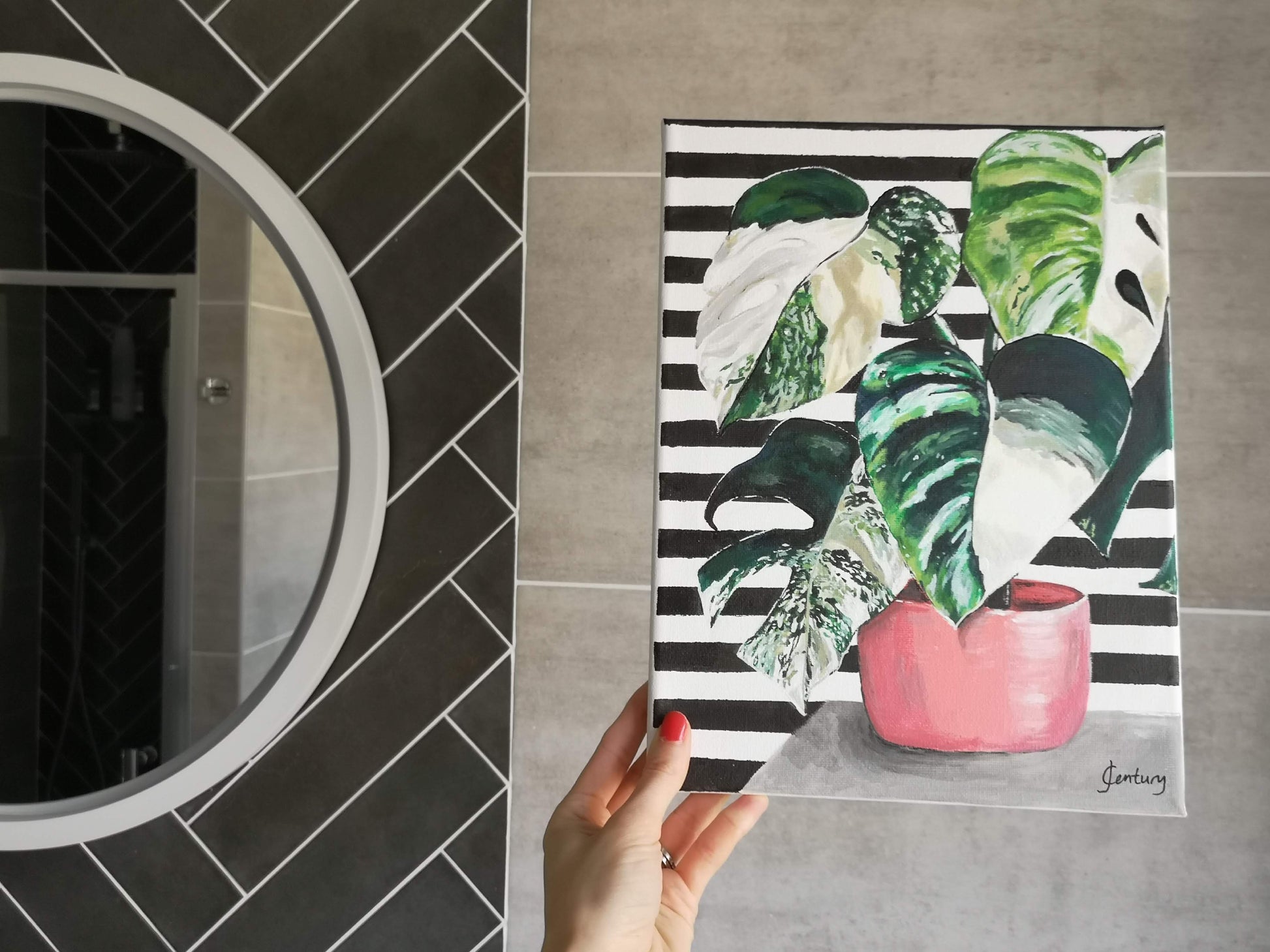 Plant painting, variegated Monstera cheese plant acrylic painting on A4 canvas with bold black and white striped pattern background. Shown in a grey and black bathroom for home decorating ideas